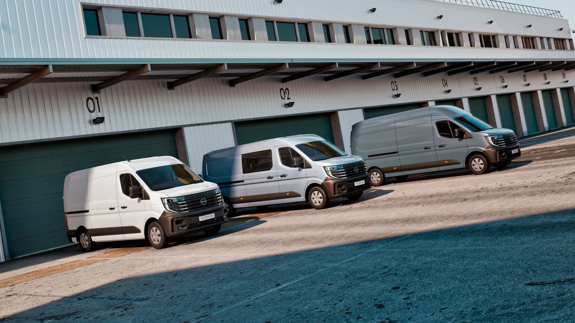 Nissan Interstar Kastenwagen (L1H1 + L2H2) und Kastenwagen mit Doppelkabine parken vor einer Lagerhalle.